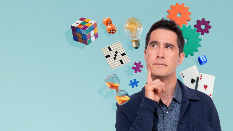 David Kwong leans over a glowing puzzle table, his hands hovering above a grid of letters as two guests watch with rapt attention