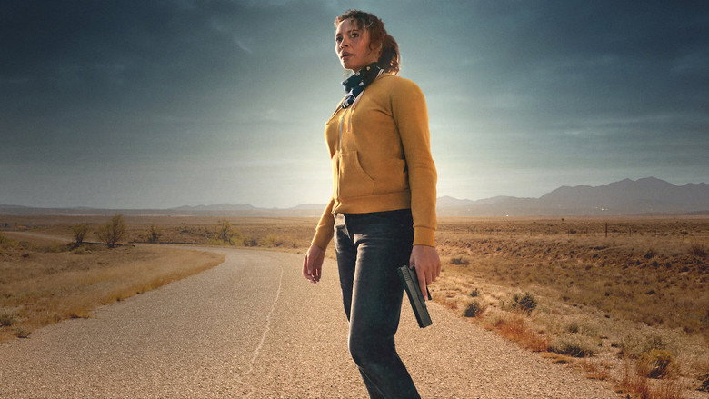 Katrina stands in the desert, the horizon stretching endlessly behind her, the weight of the sun pressing down like a judgment.