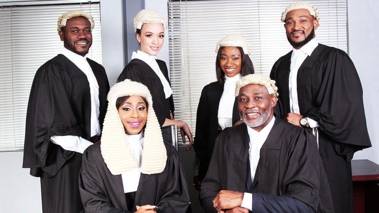A tense courtroom scene, with Remi Castle standing at the defense table, her posture rigid, while Tega watches from the gallery with a mix of pride and concern