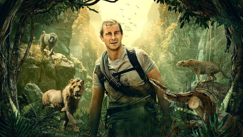 Bear Grylls crouched in tall grass, scanning the horizon with binoculars