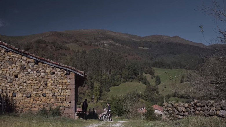 A wide shot of Héctor and Ismael in a car, the Cantabrian countryside rolling past the windows in a blur of green and gold.