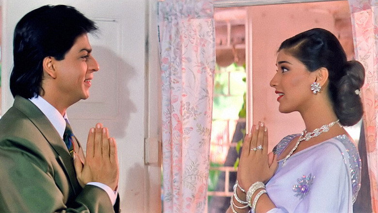 A still from *English Babu Desi Mem* showing Shah Rukh Khan and Sonali Bendre in a moment of playful tension, their faces lit with the soft glow of a sunset or stage light.