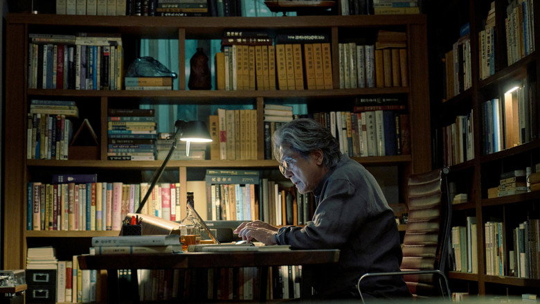A dimly lit office, the glow of a desk lamp casting long shadows. Choi Min-sik as Professor Mun-oh sits frozen, his face half in light, half in darkness, as he reads a manuscript that seems to unsettle him.
