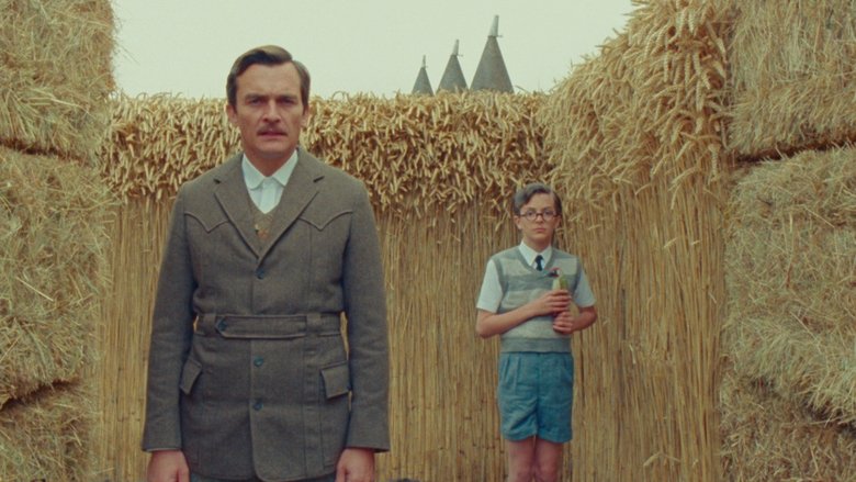 The boy stands alone on a stage-like set, the two bullies looming behind him in sharp focus.