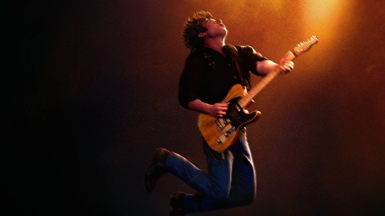 A solitary figure hunched over a guitar in a dimly lit room