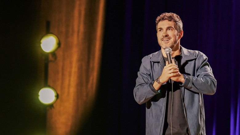 Mark Normand on stage, holding a microphone, looking intense