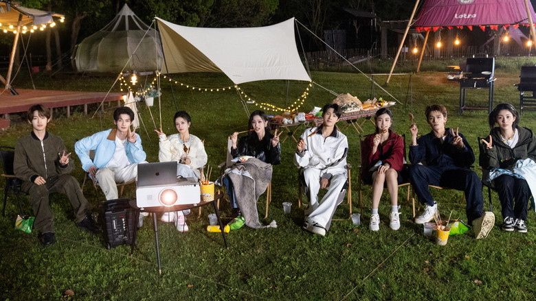 A moment of unscripted laughter, the cast huddled together under a canopy of trees, their faces lit with genuine amusement.