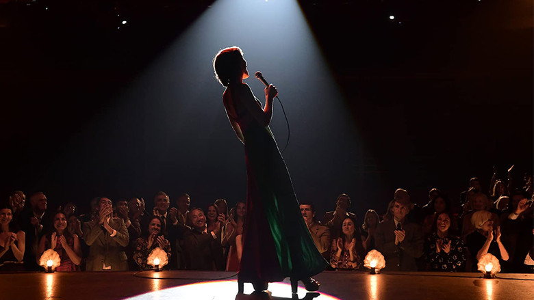 Helen Reddy, played by Tilda Cobham-Hervey, performing on stage in a shimmering gold dress, her arms raised as the spotlight catches her