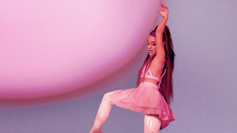 Ariana Grande on stage, bathed in pink light, her ponytail swinging as she sings into a microphone.