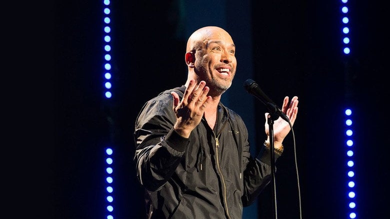 Jo Koy mid-performance, arms outstretched, face lit with the kind of manic energy that makes you lean forward in your seat