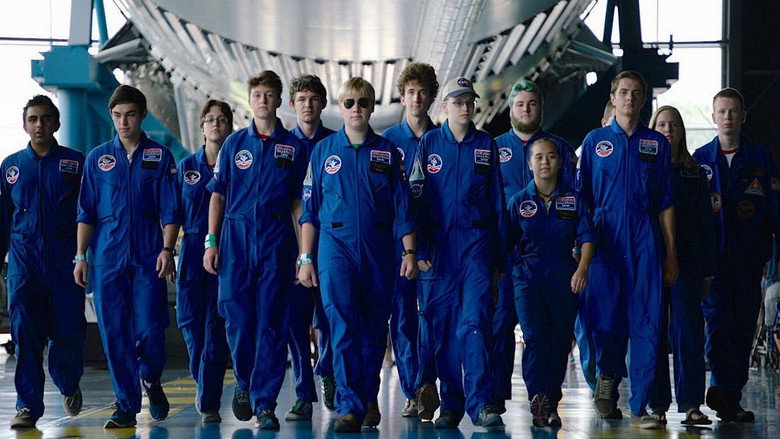 A group of young Space Camp trainees in blue jumpsuits gather around a model rocket, their faces lit with excitement and wonder.