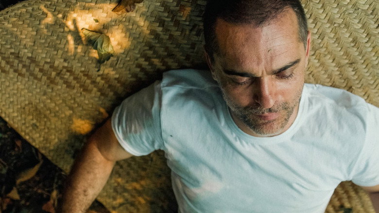 Pedro Alonso sits by a fire in the desert, his face illuminated by the flickering light, surrounded by the vast darkness of the Mexican night.