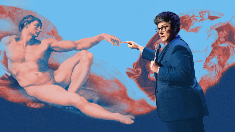 Gadsby stands on stage, arms outstretched, as if presenting a grand reveal to the audience.
