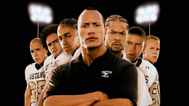 A group of young men in football gear huddle together on a field, their faces a mix of determination and exhaustion.