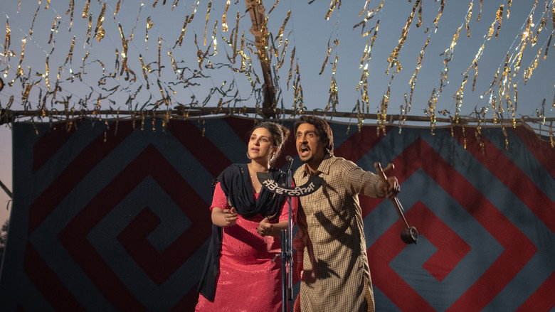 A dimly lit stage where a young Chamkila, played by Diljit Dosanjh, performs with raw intensity, his face half-lit by a single bulb