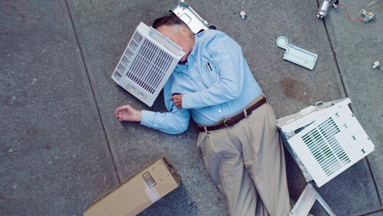 A staged death scene: Dick Johnson lies on the ground, an air conditioning unit fallen beside him, while Kirsten Johnson and crew look on.