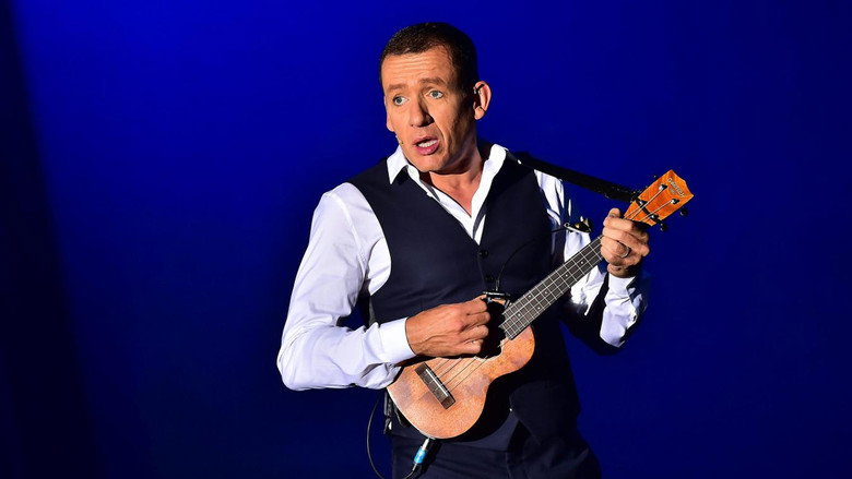 A lone spotlight illuminates Dany Boon on an empty stage, his arms outstretched as if inviting the audience into a secret.