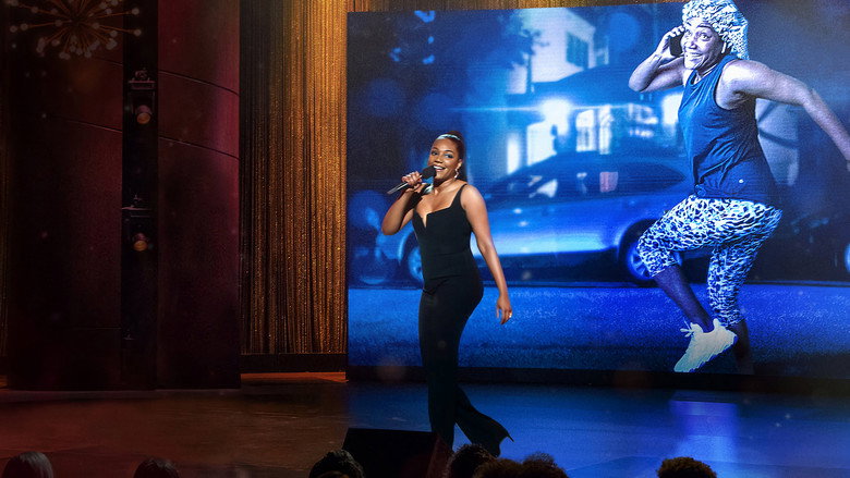 Haddish on stage, arms outstretched, bathed in warm light, as if inviting the audience into her world