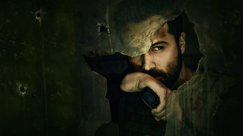 A tense interrogation scene, the dim lighting casting long shadows across Kabir Anand’s face as he leans over a bound prisoner.