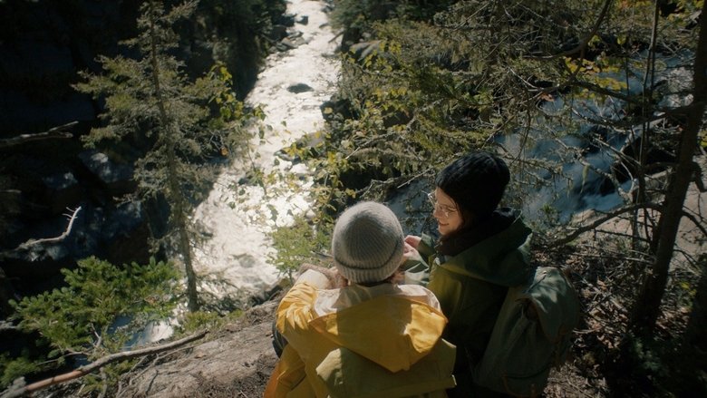 Two girls sit fully clothed in a bathtub, their knees touching under the water, as the camera lingers on their faces in a quiet, intimate moment.