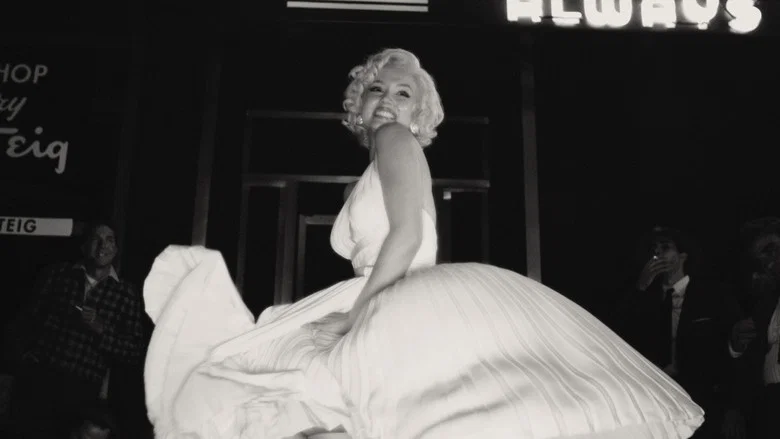 A close-up of Ana de Armas as Norma Jeane, her face half-lit, her eyes wide and unblinking, as if she's just heard a gunshot off-screen.