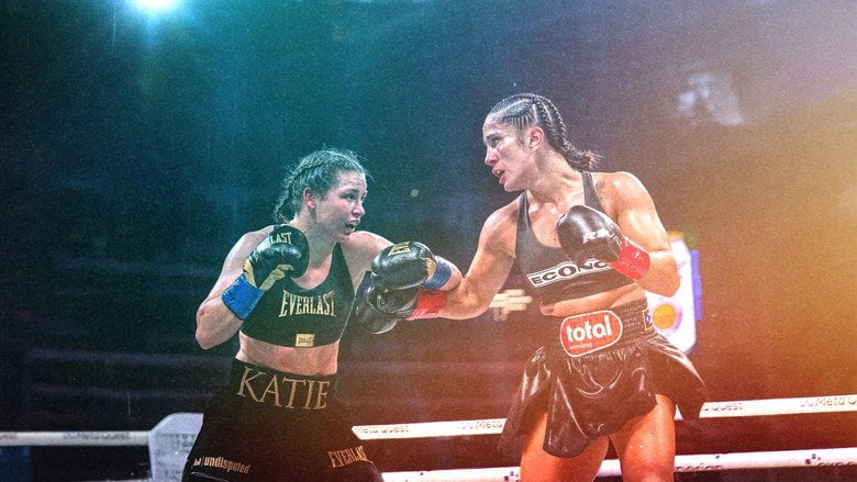 A slow-motion shot of Katie Taylor mid-punch, her face a mask of concentration, the blur of her gloves cutting through the air.