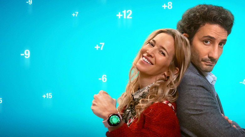 A couple sits on opposite ends of a couch, their faces illuminated by the glow of a phone screen, their expressions a mix of hope and exhaustion.