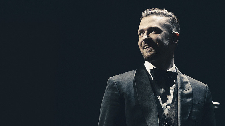 A close-up of Justin Timberlake on stage, bathed in blue and purple lights, his expression a mix of exhaustion and joy