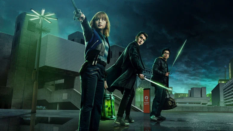 The trio stands in the dim glow of a streetlamp, their breath visible in the cold London air, the weight of the unseen pressing in around them.