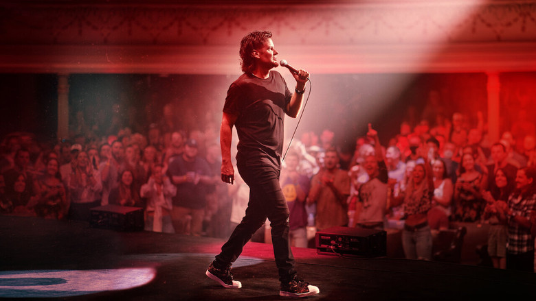 Theo Von on stage, bathed in warm light, mid-gesture