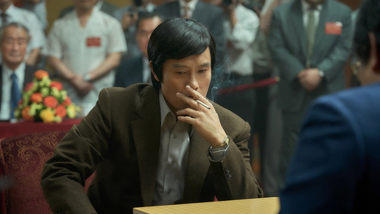 A close-up of Lee Byung-hun’s face, half-lit by the glow of a Go board, his expression caught between concentration and something like grief.