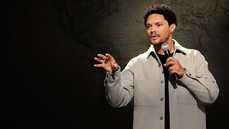 Trevor Noah on stage, mid-gesture, in a sharp suit against a dark background