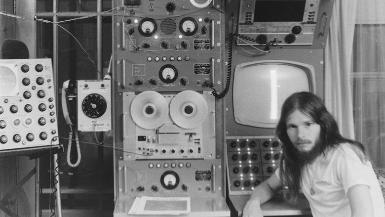 John Shepherd adjusts his homemade radio equipment, the glow of dials illuminating his focused expression.