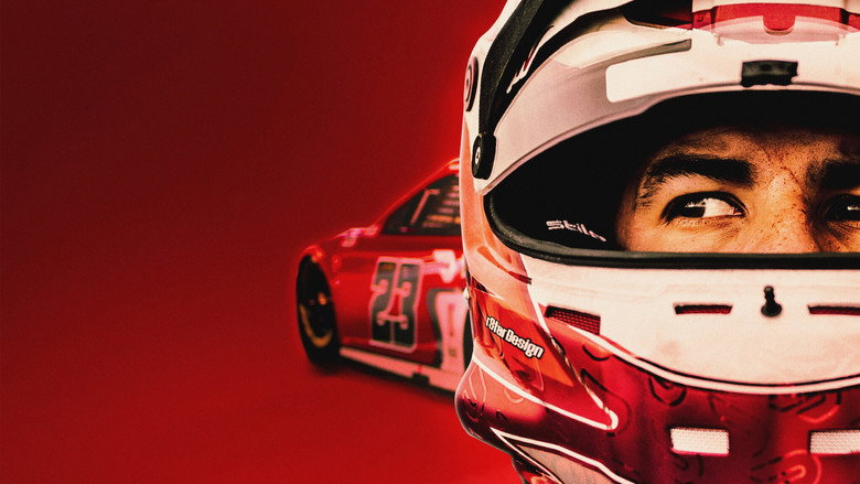 A close-up of Bubba Wallace in his racing suit, helmet under his arm, staring into the distance with a mix of determination and exhaustion.