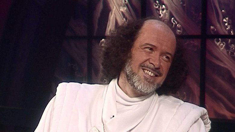 A close-up of Raël speaking to a crowd, his hands raised in emphasis, the light catching the silver in his hair.