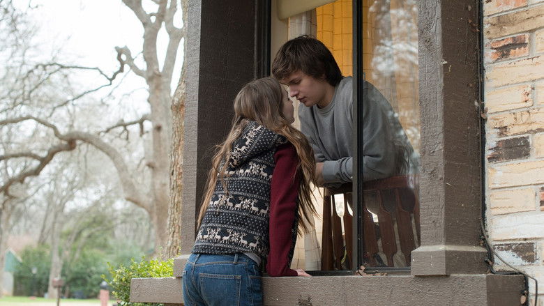 Two teenagers sitting together outside, both looking down at their separate phones
