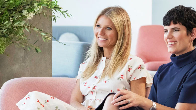 A dimly lit room where Gwyneth Paltrow and two Goop employees sit in a circle, hands clasped, eyes closed, as if channeling the universe’s Wi-Fi signal.