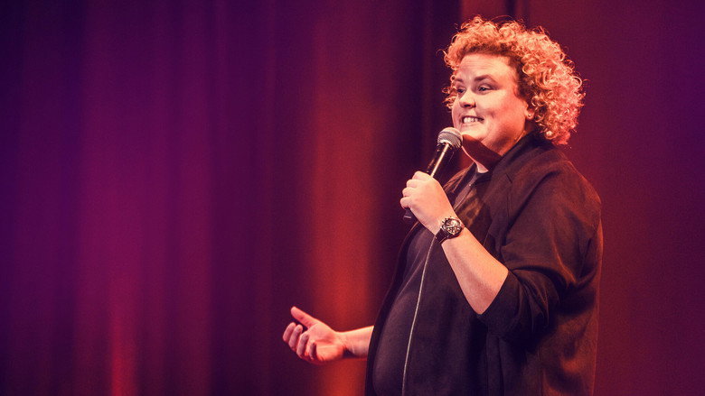 Fortune Feimster on stage, mid-laugh, bathed in warm light