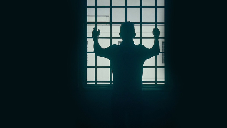 A dimly lit interrogation room, the camera angled to show only the back of a man’s head as he sits across from investigators.