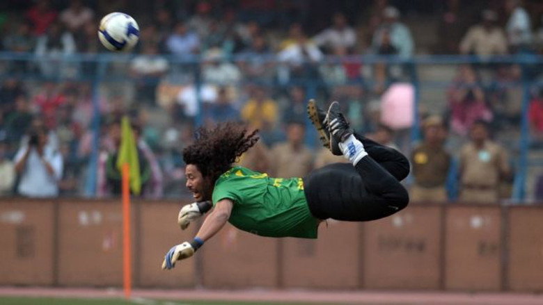 A young René Higuita in an Atlético Nacional jersey, mid-dribble, with defenders trailing behind him