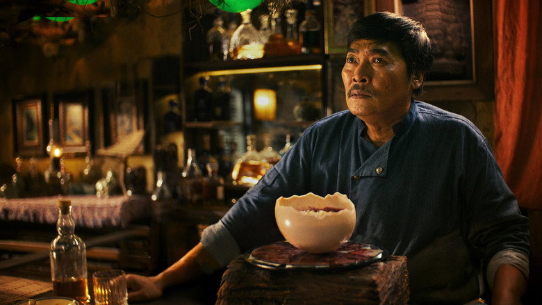 The chef’s knife pauses mid-slice, the raw meat glistening under the diner’s dim, saturated light.