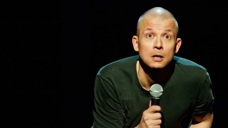 Jim Norton on stage, mid-joke, his face lit with the kind of smirk that suggests he’s already three steps ahead of the audience.