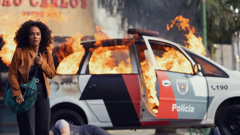 Cristina navigating a dimly lit, neon-drenched hallway