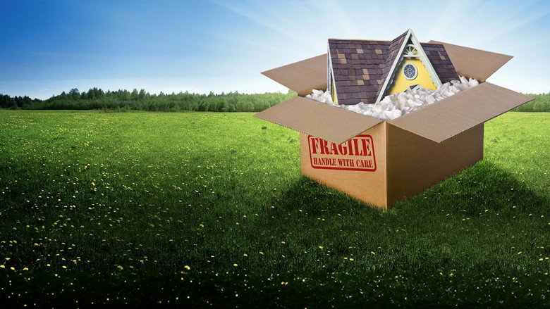 A tiny house on wheels, its wooden exterior glowing in the golden hour light, perched on a grassy hill with mountains in the distance.