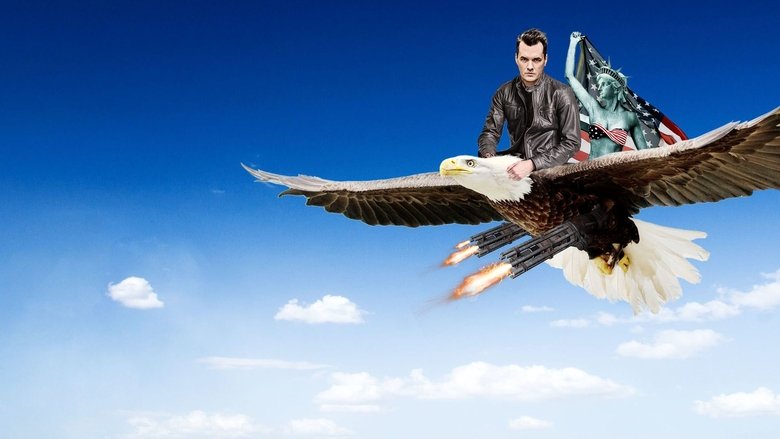 Jim Jefferies on stage, mid-gesture, his face lit with the kind of smirk that suggests he’s about to say something you’ll regret laughing at