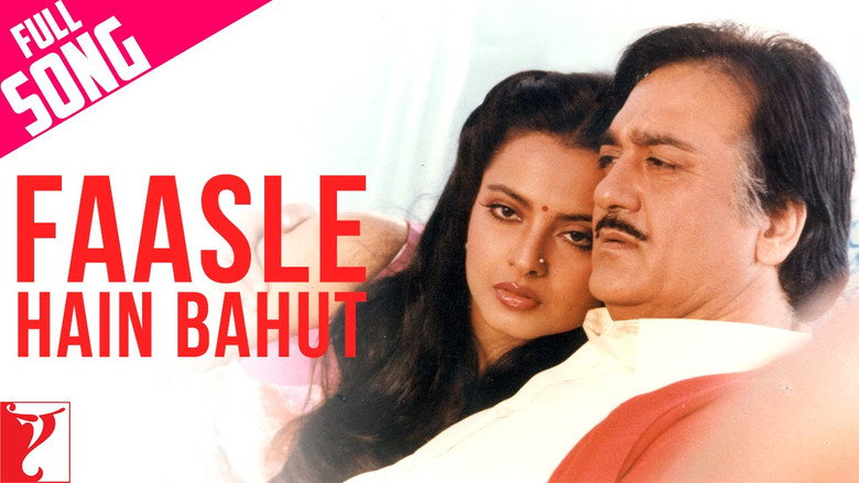 A still from *Faasle*, showing a couple standing apart in a lush, misty landscape, their bodies angled away from each other but their eyes locked in silent longing.