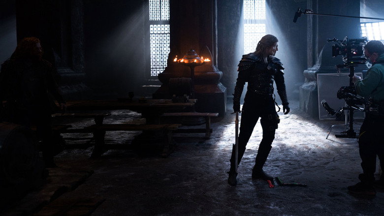 A close-up of Geralt’s redesigned armor, its leather straps and metal plates worn and uneven, resting on a mannequin in a dimly lit workshop