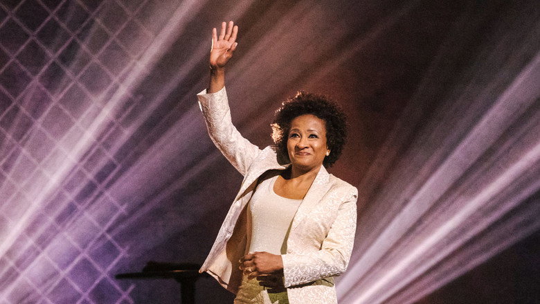 Wanda Sykes on stage, mid-laugh, gesturing with her hands as if she's just dropped a truth bomb.