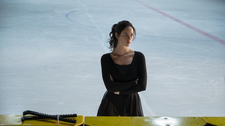 Kat Baker mid-spin, her face a blur of concentration and exhaustion, the rink’s lights reflecting off the ice like shattered glass