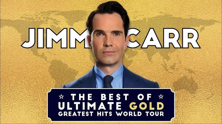 Jimmy Carr on stage, bathed in warm light, a faint smirk playing on his lips as he delivers a punchline